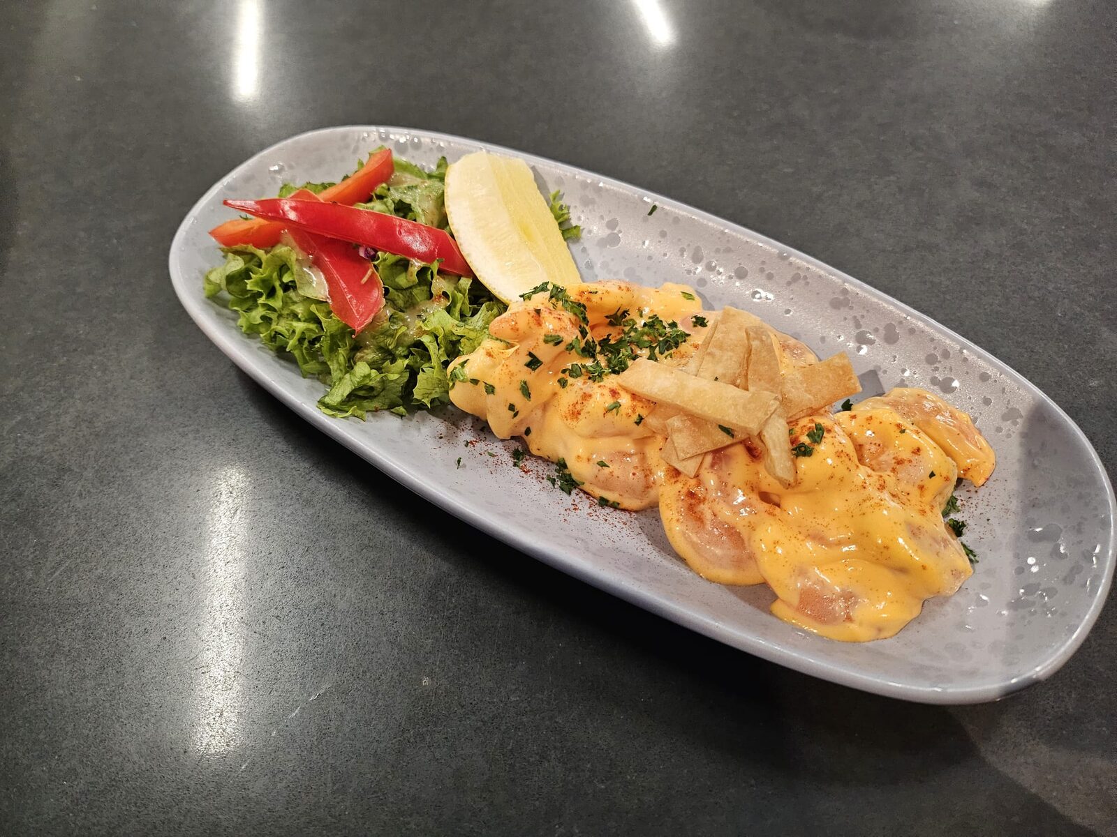 Prawns in a creamy sauce with tortilla strips and salad